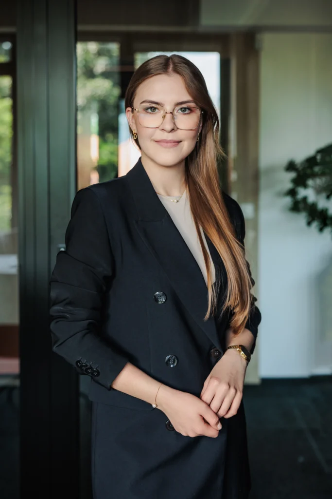 Kobieta w długich włosach w czarnej marynarce i okularach, sesja zdjęciowa. w krakowskiej kancelarii prawniczej