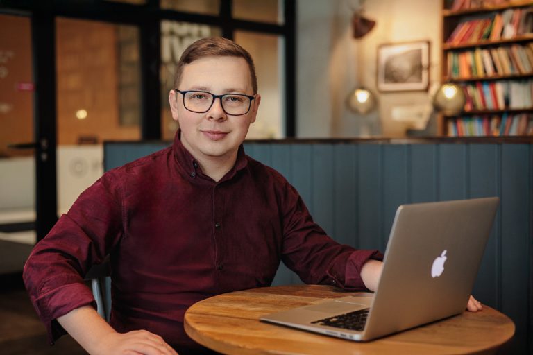 mężczyzna przy stole pracujący przy laptopie